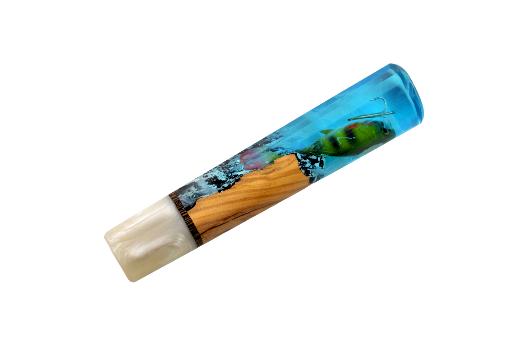 Le modèle « Made in Turkey Custom Wa-Handle #629 » (142 mm, standard) se compose d'une partie en résine bleue évoquant l'eau, ornée d'un leurre de pêche vert, d'un segment en bois rappelant le manche d'un couteau sur mesure, et d'une extrémité blanc nacré, le tout présenté sur fond blanc.